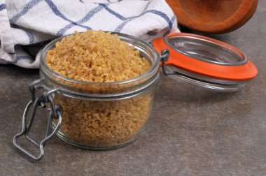 Kavanoz dolusu açık ham bulgur buğdayı gri arkaplanı kapatır