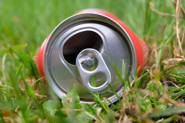 Пустую банку бросили в траву крупным планом.