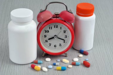 İlaçlar ve plastik şişeler içeren alarmlı saat.