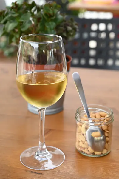 Glass of white wine with a jar of peanuts placed on a table close-up