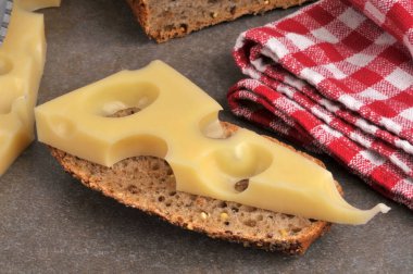 Bir dilim ekmeğin üzerine bir parça Emmental peyniri yakın plan.