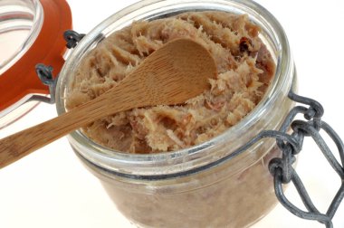 Beyaz arka grubuna yakın bir tahta kaşıkla bir kavanoz rillet.