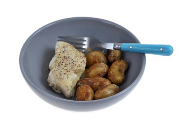 Hardal soslu morina filetosu ve beyaz arka planda çatalla servis edilen patatesler.