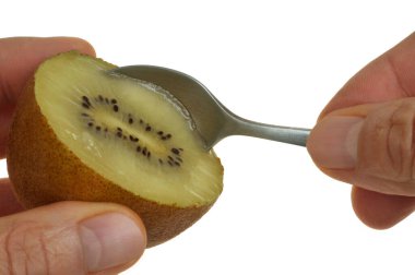Beyaz arka planda bir kaşıkla sarı kivi yemek. 