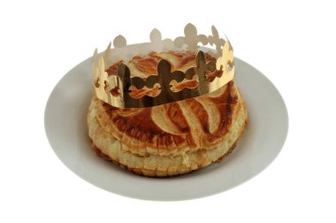 Galette des Rois ve tacı beyaz arka planda yakın plan bir plakada. 