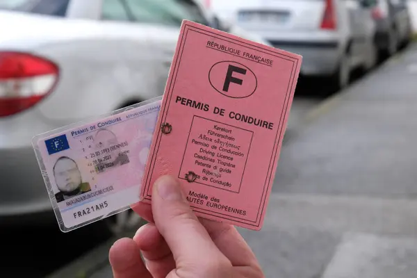 Eski ve yeni ehliyetin arka planında bulanık arabalar var.