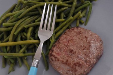 Biftek kıymalı, yeşil fasulyeli ve çatalla yakın plan.