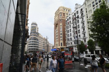 Madrid 'in Gran Via caddesinde yürüyen insanlar neo-rönesans tarzı binalarla dolu. 