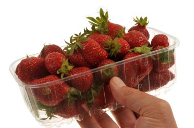 Beyaz arka planda el ele tutuşmuş plastik çilek kabı.