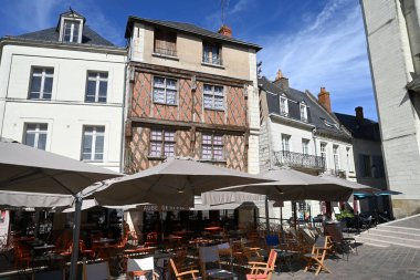 Cafe terraces on Saint-Pierre square in the town of Saumur with a half-timbered house in the background clipart