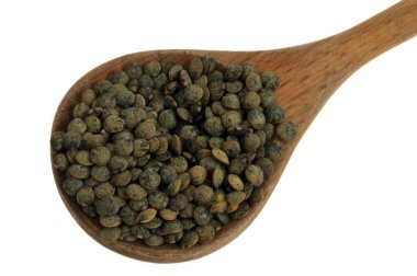 Tahta kaşık kurutulmuş kabarık mercimek. Beyaz arka planda izole edilmiş yakın plan.