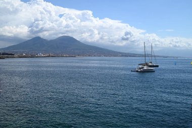 Napoli Körfezi 'nin arka planında yelkenli tekneleri ve Vesuvius volkanı var.