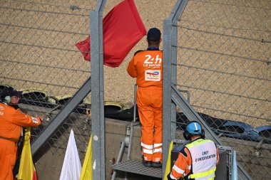24 Saat Le Mans 'ın güvenlik görevlisi kırmızı bayrak sallayarak yarışın bittiğini işaret ediyor.