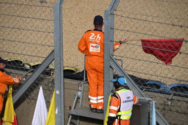 24 Saat Le Mans 'ın güvenlik görevlisi kırmızı bayrak sallayarak yarışın bittiğini işaret ediyor.