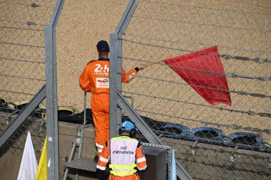 24 Saat Le Mans 'ın güvenlik görevlisi kırmızı bayrak sallayarak yarışın bittiğini işaret ediyor.