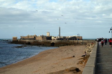 Endülüs 'teki Castillo de San Sebastian' a giden deniz duvarında yürüyen turistler