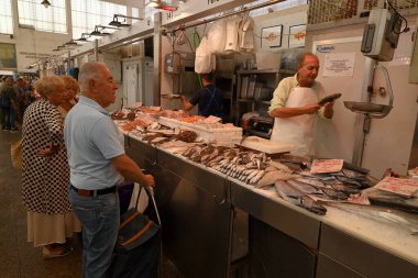 Cadiz 'in merkez pazarında bir balıkçı ve müşterilerle balık tezgahı kuruyor.