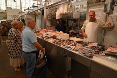 Cadiz 'in merkez pazarında bir balıkçı ve müşterilerle balık tezgahı kuruyor.