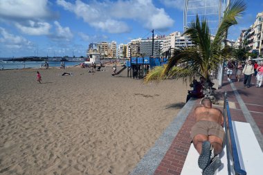 Las Palmas de Gran Canaria 'daki Las Canteras plajının önündeki bankta yatan adam.