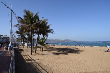 Las Palmas de Gran Canaria 'da güneşli bir günde turistlerle Las Canteras sahilinde kentleşmiş.