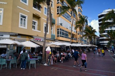Las Palmas de Gran Canaria 'daki Las Canteras gezinti alanındaki bar ve restoranların teraslarında oturan turistler