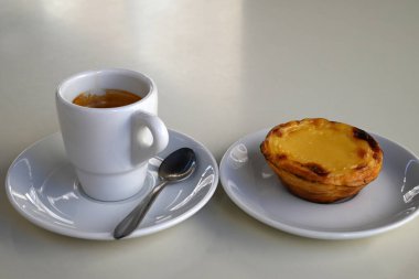 Pasteis de nata bir fincan espressonun yanında.