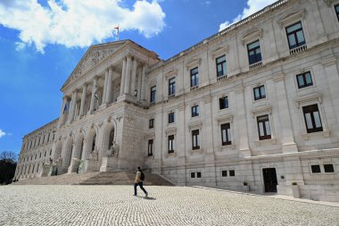 Lizbon 'daki Sao Bento Sarayı' nın önünde yürüyen adam.