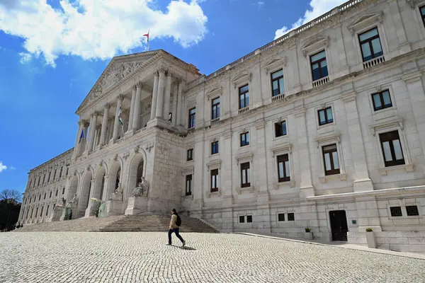 Lizbon 'daki Sao Bento Sarayı' nın önünde yürüyen adam.