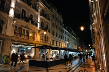 Geceleri Lizbon 'daki Augusta Caddesi' nde birkaç turist ve boş restoran terasları var.