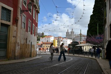 Arka planda Sao Vicente de Fora Manastırı ile Lizbon 'da Rua da Mata' yı geçen genç kadınlar 