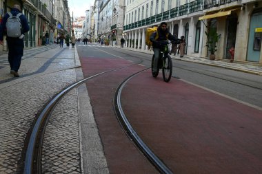 Lizbon 'da Prata Caddesi' nde bisiklet teslimatçısı bir adamla tren rayları.