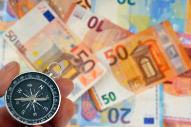 Avro 'nun bulanık banknotlarının arka planında elinde bir pusula bulunan mali yönlendirme kavramı