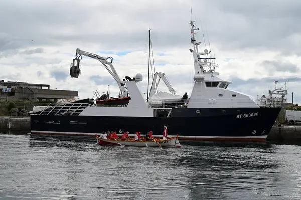 Geleneksel kayık ekibi ile Sete limanında bir ton balığı teknesinin yanından geçiyor.