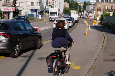 Güneşli bir günde Vannes şehrinde bisiklet süren bir kadın.