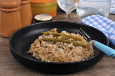 Ev yapımı yeşil kuşkonmaz risotto tabakta servis edilen çatalla yakın plan.