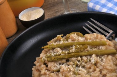 Bir tabak ev yapımı yeşil kuşkonmaz risotto ve yakın plan çatal.