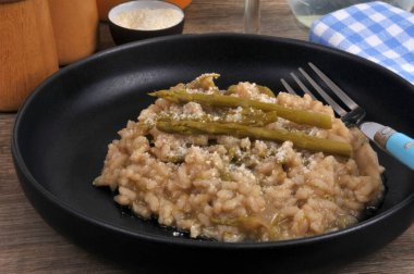 Ev yapımı yeşil kuşkonmaz risotto tabakta servis edilen çatalla yakın plan.