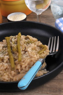 Ev yapımı yeşil kuşkonmaz risotto tabakta servis edilen çatalla yakın plan.