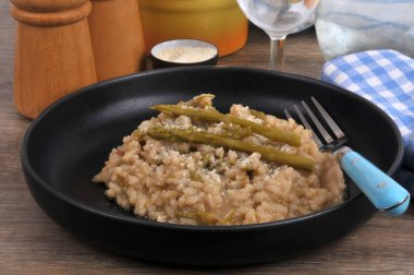 Bir tabak ev yapımı yeşil kuşkonmaz risotto ve yakın plan çatal.