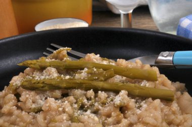 Bir tabak ev yapımı yeşil kuşkonmaz risotto ve yakın plan çatal.