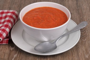 Bir kase ev yapımı gazpacho, tahta arka planda kaşıkla yakın plan.