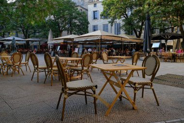 Montpellier 'deki Jean Jaures Meydanı' nda bir kafe terasında kelepçelenmemiş masa ve sandalyeler.