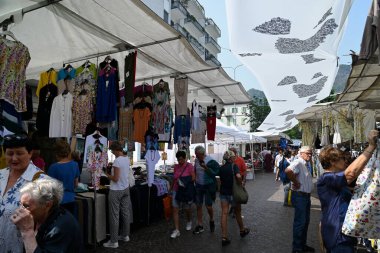 Turistler ve müşteriler Como pazarındaki tezgahlarda dolaşıyorlar.