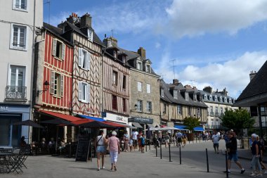 Lucien Laroche Meydanı 'nda turistlerle dolu kafe terasları ve dükkanlar.