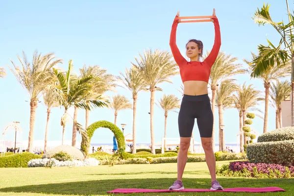 Fitness woman works out with fitness rubber bands in a beach location. Healthy lifestyle. Outdoor workout.Fit woman exercising with fitness rubber band in the park.