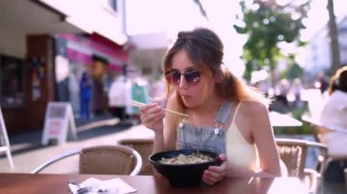 Asya restoranında bir kase etli erişte yiyen bir kadın. Çin çorbası yiyor. Erişte, ot ve etten oluşuyor. Vietnam usulü erişte çorbası, ph..