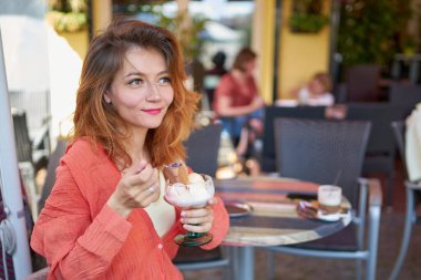 Güzel bir kadının yakın plan portresi Avrupa 'daki açık hava restoranında dondurma yemekten zevk alır. Bir kafede turist bir kadın açık havada çöl keki dondurmasının tadını çıkarıyor..                               