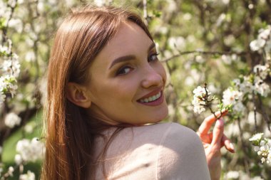 Kiraz çiçeği bahçesinde poz veren güzel bir kızın portresi.