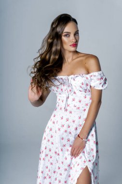 Stüdyoda beyaz arka planda poz veren muhteşem genç bir kadın.