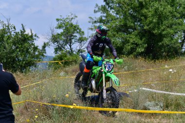 25 Haziran 2023, Veles, Makedonya. Enduro ekstrem moto yarışında sürücüler zorlu bir arazide lastiklerin üzerinden atlayarak ve dağ yollarında 40 kilometrelik bir sürüş yaparak yarıştılar..